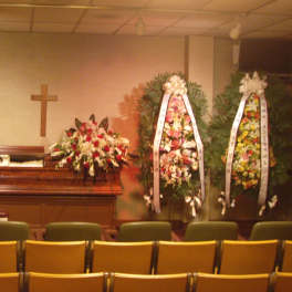 Funeral chapel with casket sprays and standing floral wreaths around a casket