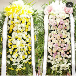 Two tall floral standing sprays with yellow and pink-white roses and ribbons