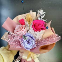 Hand-tied bouquet of colorful roses with decorative accents and pink wrapping