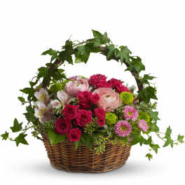 Basket of pink and white flowers with ivy draped over the handle