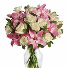 Pink lilies and white roses arranged in a clear glass vase