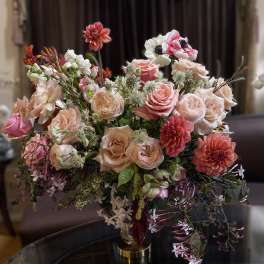 Mixed pink and peach floral arrangement in a gold vase