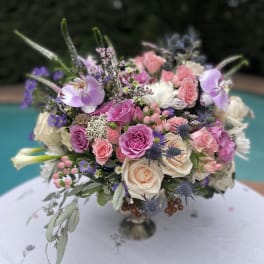 Large bouquet of pink and cream roses with purple orchids in a vase