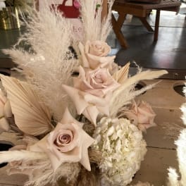 Blush roses and white hydrangea with tall pampas grass in a low arrangement