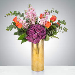 Bouquet of purple hydrangea and orange roses in a gold vase