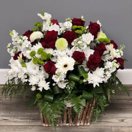 Red roses and white flowers in a rustic basket arrangement