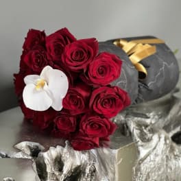 Bouquet of red roses with a white orchid on dark wrapping