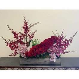 Red roses and pink orchids arranged in a rectangular wooden box