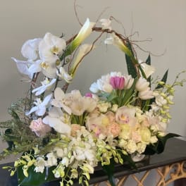 Large floral basket with white orchids, tulips, and pale roses