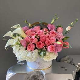 Pink roses and white hydrangeas arranged in a round box
