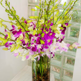 Tall vase arrangement of purple, white, and pale pink orchids