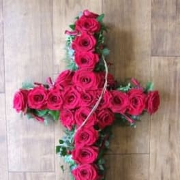 Cross-shaped arrangement of hot pink roses with greenery