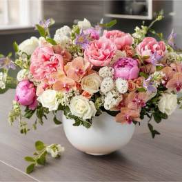 Pink and white floral arrangement in a white bowl vase