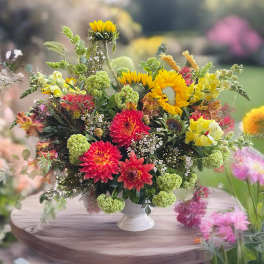Colorful mixed flower arrangement in a white pedestal vase