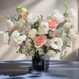 Large bouquet of white and blush flowers in a black vase