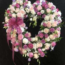 Heart-shaped floral wreath of pink, white, and purple roses with a ribbon bow