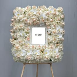 Floral photo frame covered in white and blush orchids on an easel