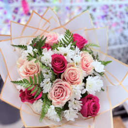 Bouquet of pink and white roses with white daisies in pale wrapping