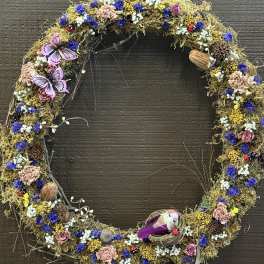 A dried floral wreath with purple, pink, white, and yellow accents.