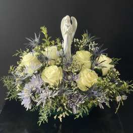 Cream roses and lavender flowers arranged around an angel figurine