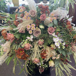 Large mixed floral arrangement with pink roses and orange mums in a black container