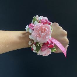 Pink floral wrist corsage with ribbon on a person's wrist