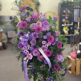 Standing spray of purple and pink flowers with lavender ribbons