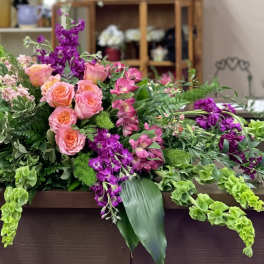 Large floral arrangement with pink roses and purple flowers on a table