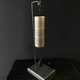 Gold wind chime hanging from a metal stand on a dark base