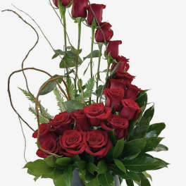 Red roses arranged in a black vase with curly branches
