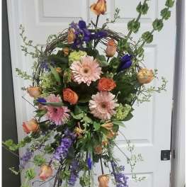 Tall floral wreath with pink gerberas, orange roses, and purple blooms