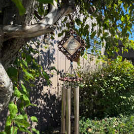 Decorative wind chime hanging from a tree branch outdoors