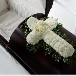 White floral cross arrangement on a dark casket