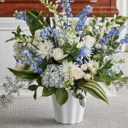 White and blue floral arrangement in a white vase