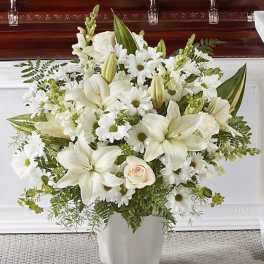 White lilies and daisies arranged in a white vase