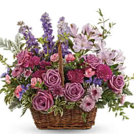 Basket arrangement of purple roses and lilies with tall purple spikes