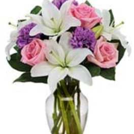 Pink roses and white lilies in a clear glass vase