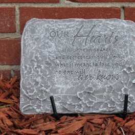 Gray memorial stone with an engraved heart quote on a brick wall