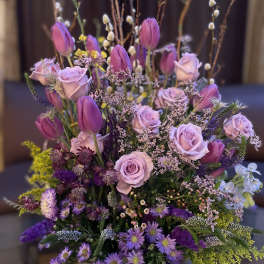 Lavender roses and purple tulips in a round vase with mixed filler flowers