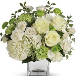 White roses and green carnations in a clear glass vase
