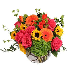 Bright mixed bouquet in a round glass vase with roses, gerbera daisies, and sunflowers