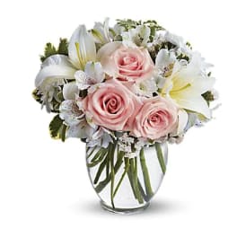 Pink roses and white lilies arranged in a clear glass vase