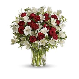 Red roses and white alstroemeria in a clear glass vase