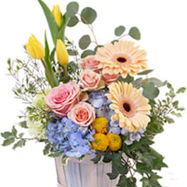 Mixed bouquet in a silver container with pink roses, yellow tulips, and peach daisies