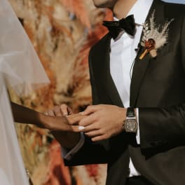Bride and groom exchanging rings, with a boutonniere on the groom's lapel