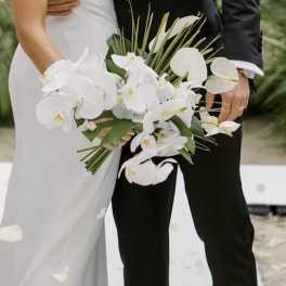 Bride and groom holding a white orchid wedding bouquet