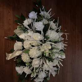 White floral spray with roses and chrysanthemums on a wooden surface