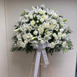 Large white funeral spray on an easel with a family ribbon