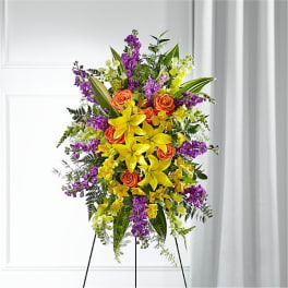 Standing floral spray with yellow lilies, orange roses, and purple flowers