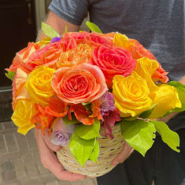Basket of bright roses in yellow, orange, and pink